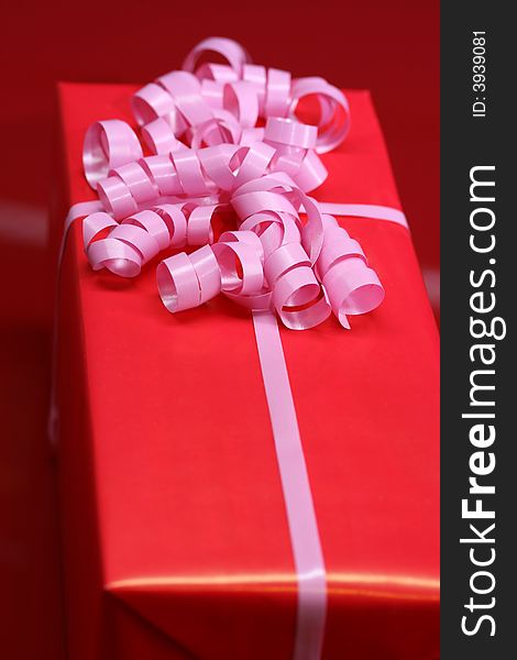 A red wrapped gift with pink ribbon. A red wrapped gift with pink ribbon