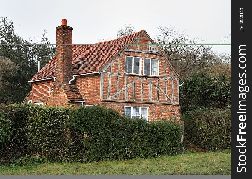 Quaint Timber Framed English Rural Cottage with Hedgrerow and grass verge to the front