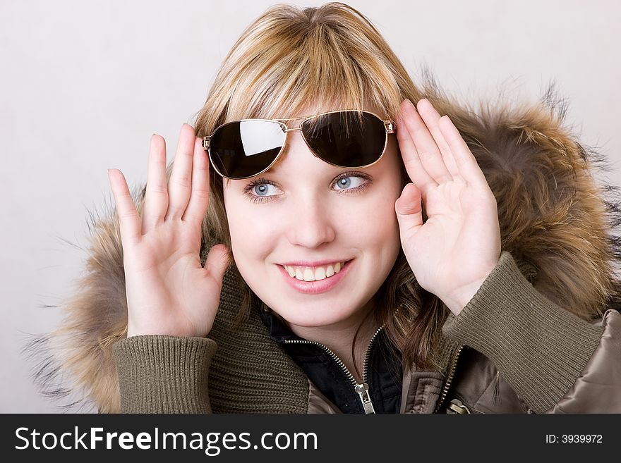 Playful girl with sunglasses in a jacket with a collar of fur