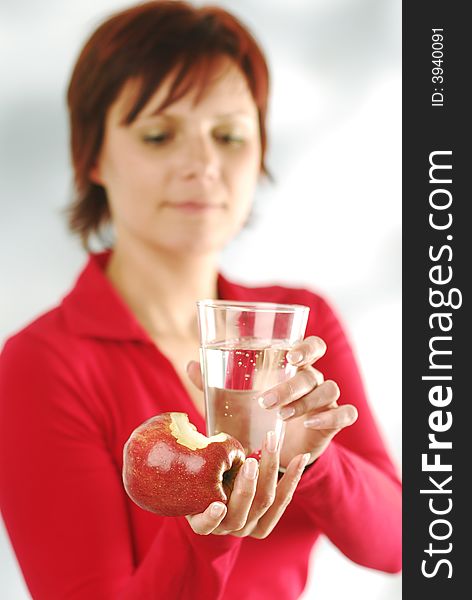 A woman with glass of water and apple. A woman with glass of water and apple