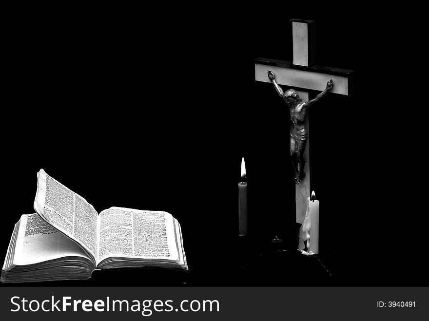 Stark black and white image of a prayer crucifix with two candles set out before a bible open to the book of Matthew. Stark black and white image of a prayer crucifix with two candles set out before a bible open to the book of Matthew