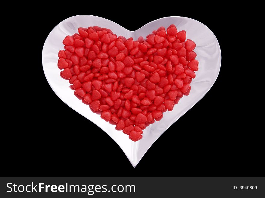 Silver heart shaped bowl filled with red candy hearts