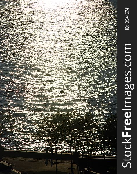 Sunset. Hudson river. Two silhouettes of people and trees on a footpath