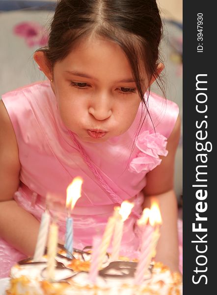 The girl in a pink dress blows into candles