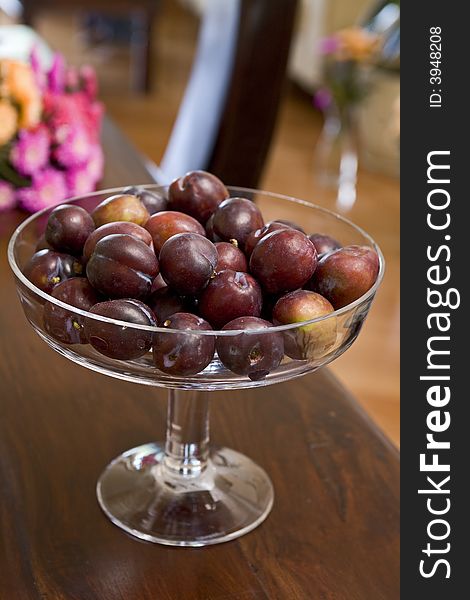 Plums in glass receptacle on table