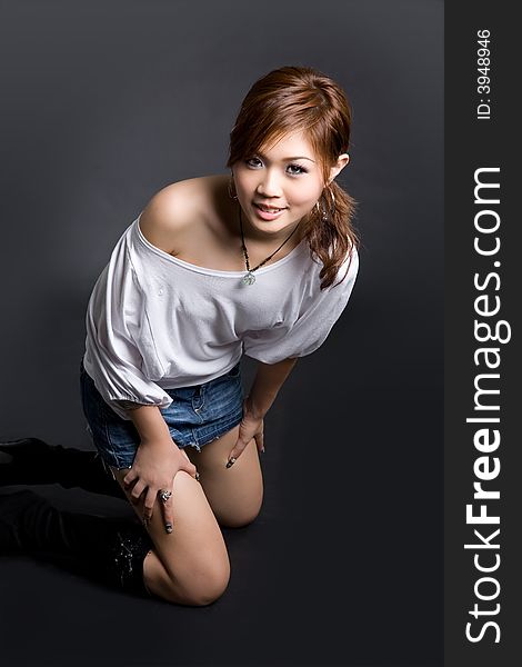 A fashionable young girl pose by kneeling on the floor. A fashionable young girl pose by kneeling on the floor
