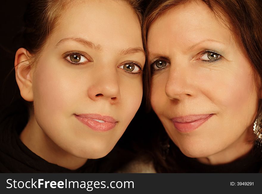 Mother and daughter portrait together on black background