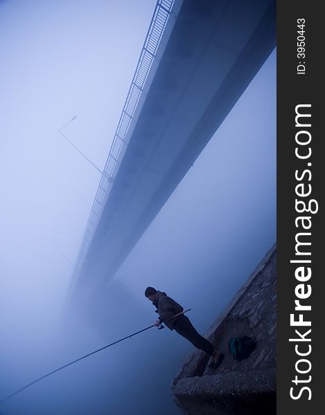 Fishing below the bridge in the fog