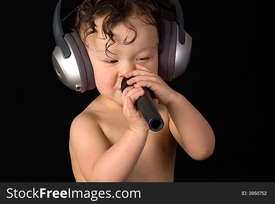 Sing baby with headphone and microphone,isolated on a black background. Sing baby with headphone and microphone,isolated on a black background.