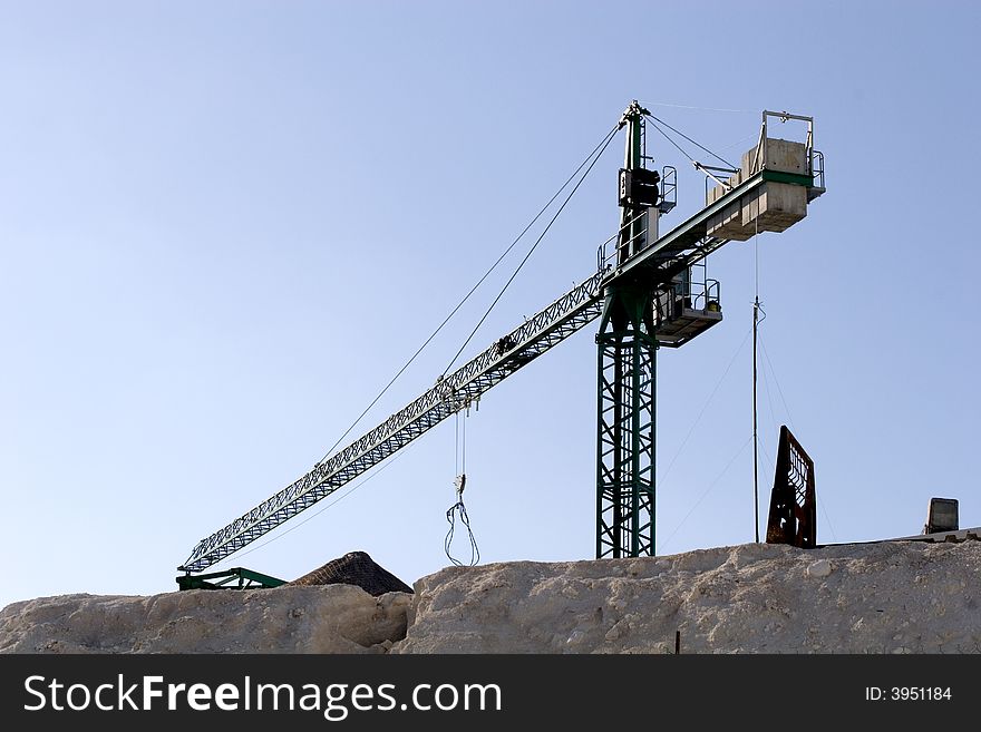 A crane at a construction site on top of a sand cliff. A crane at a construction site on top of a sand cliff