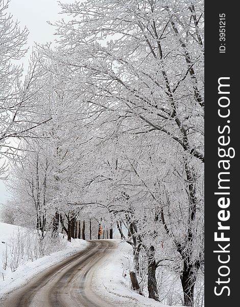 Slippery winter road with a turning among tree and mountains