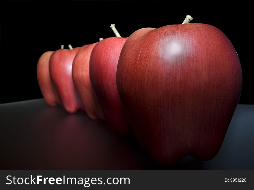 Red plastic apples over mirror and selective focus