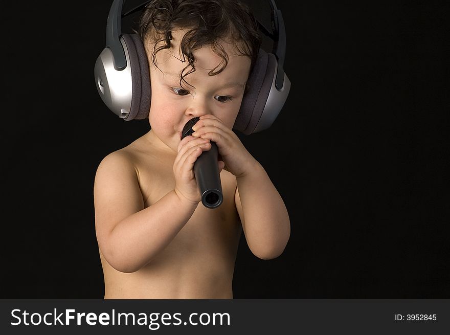 Sing baby with headphone and microphones, on a black background. Sing baby with headphone and microphones, on a black background.