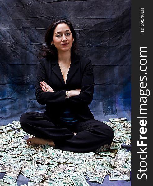 Rich woman sitting with crossed arms in money isolated on a dark background. Rich woman sitting with crossed arms in money isolated on a dark background