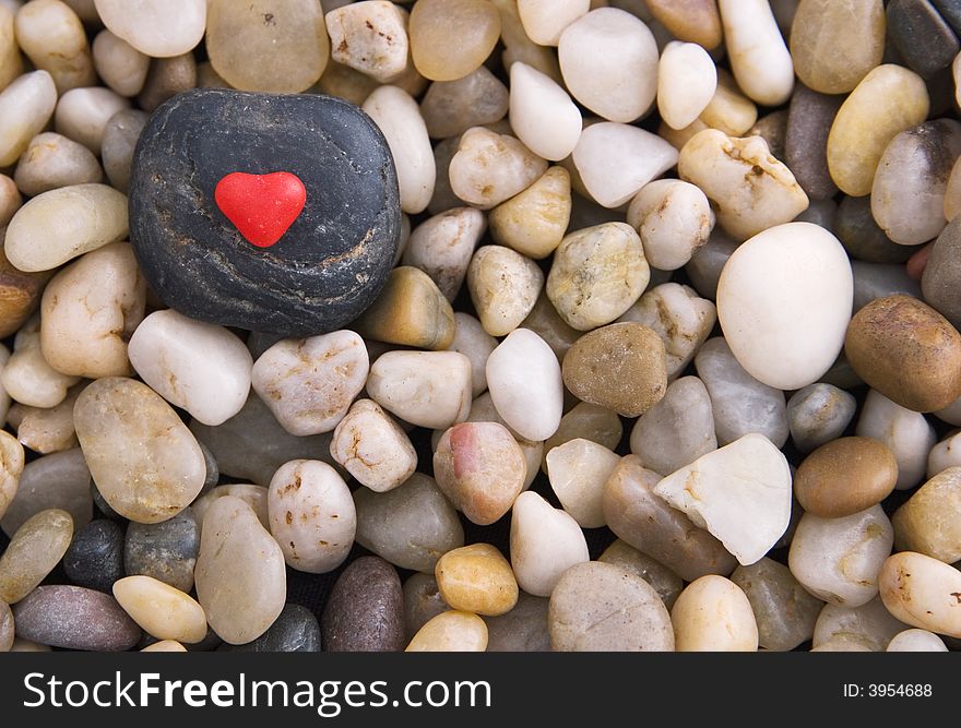 Red candy heart on a black stone surrounded by gravel