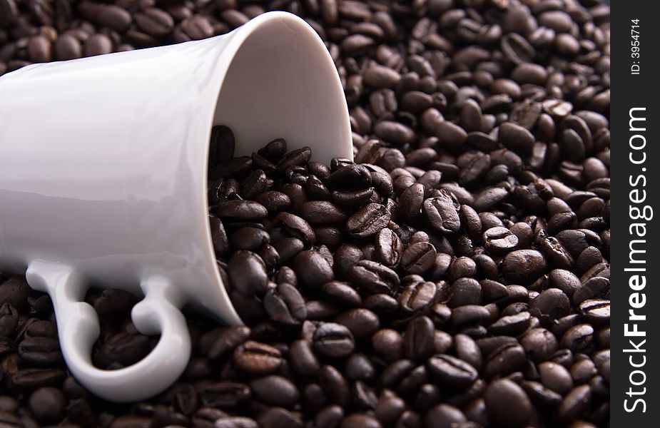 Coffee beans spilling out of a white coffee cup