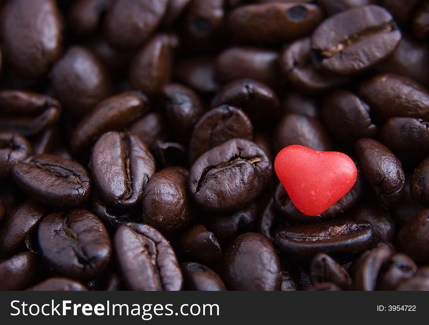 Close up of a red candy heart in coffee beans