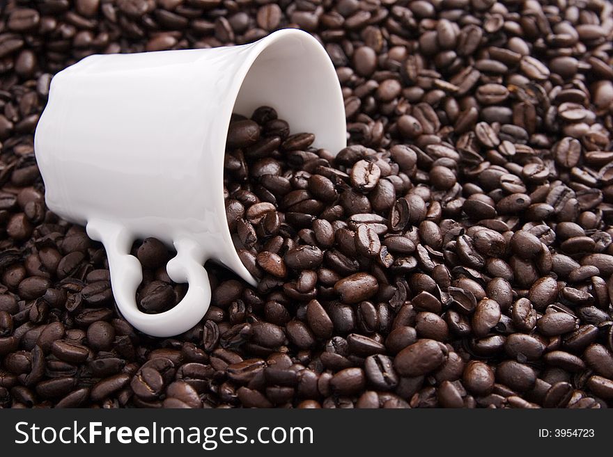 Coffee beans spilling out of a white coffee cup