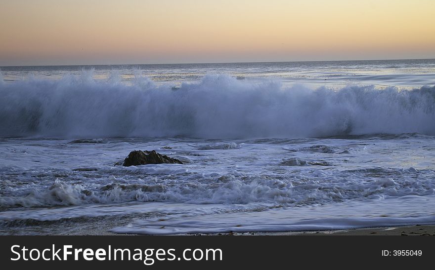 Waves crashing onto shore at sunset. Waves crashing onto shore at sunset.