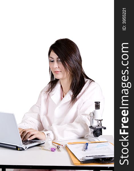 Lab tech working on a laptop and a microscope. Lab tech working on a laptop and a microscope.