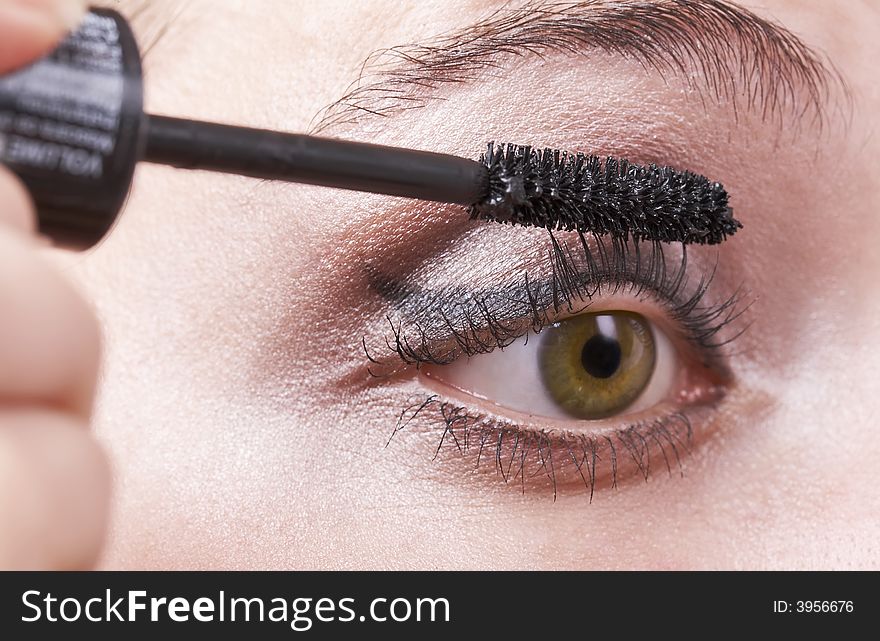 Woman applying mascara, volume brush, green eye