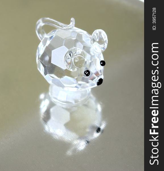A small souvenir in the form of a glass mousy. Reflection from a metal ridge surface is visible.