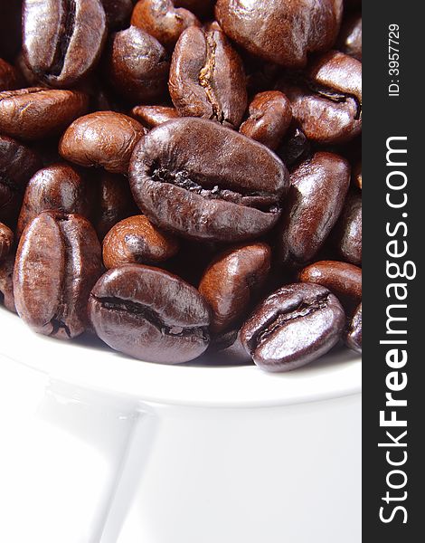 Close up of roasted coffee beans in a white cup. Close up of roasted coffee beans in a white cup.