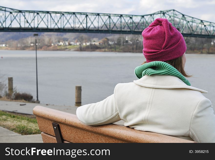 Picture of a girl waiting on the bench admiring the scenery on a cold day. Picture of a girl waiting on the bench admiring the scenery on a cold day