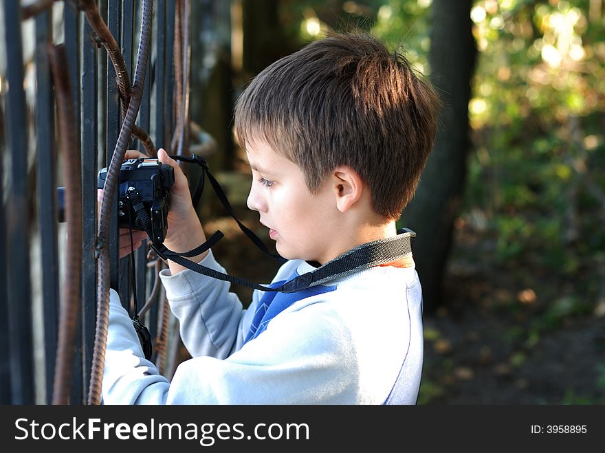 Boy concentrated holds a black digital camera in hands. Boy concentrated holds a black digital camera in hands