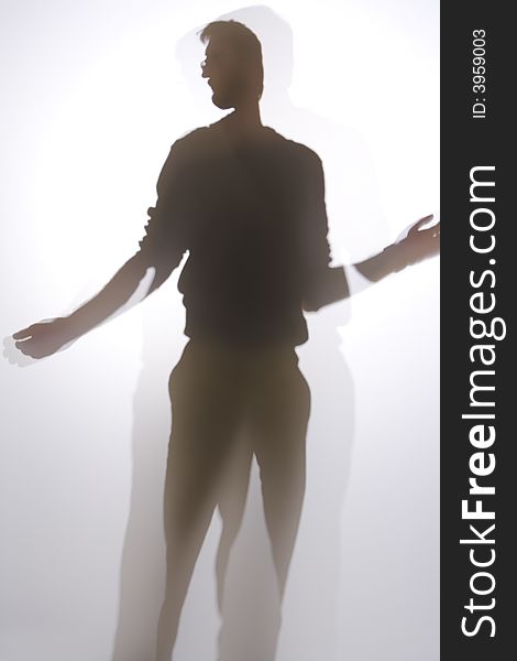 Silhouette of man in front of screen or window reaching up. His arms are extended on each side. Silhouette of man in front of screen or window reaching up. His arms are extended on each side.