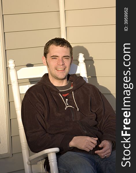 Here is a photo of young man enjoying the setting sun on a rocking chair. Here is a photo of young man enjoying the setting sun on a rocking chair