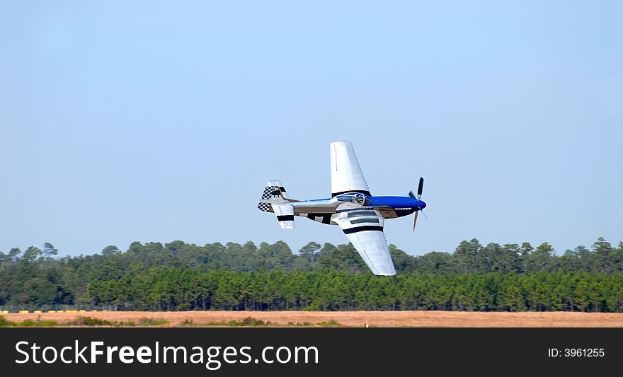 A World War 2 P-51 Mustang flying low to the ground at high speed. A World War 2 P-51 Mustang flying low to the ground at high speed