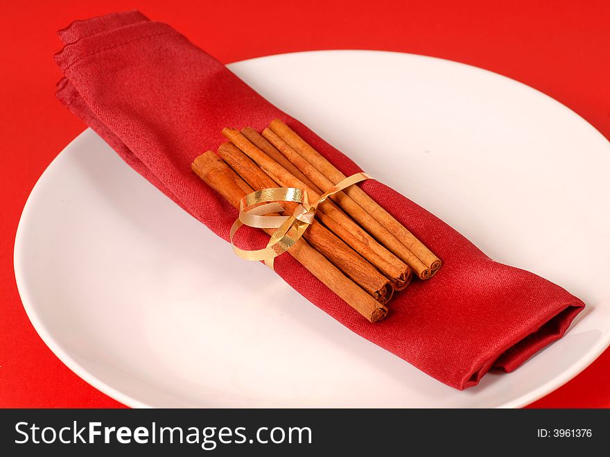 Cinammon sticks wrapped in a red napkin on a white plate