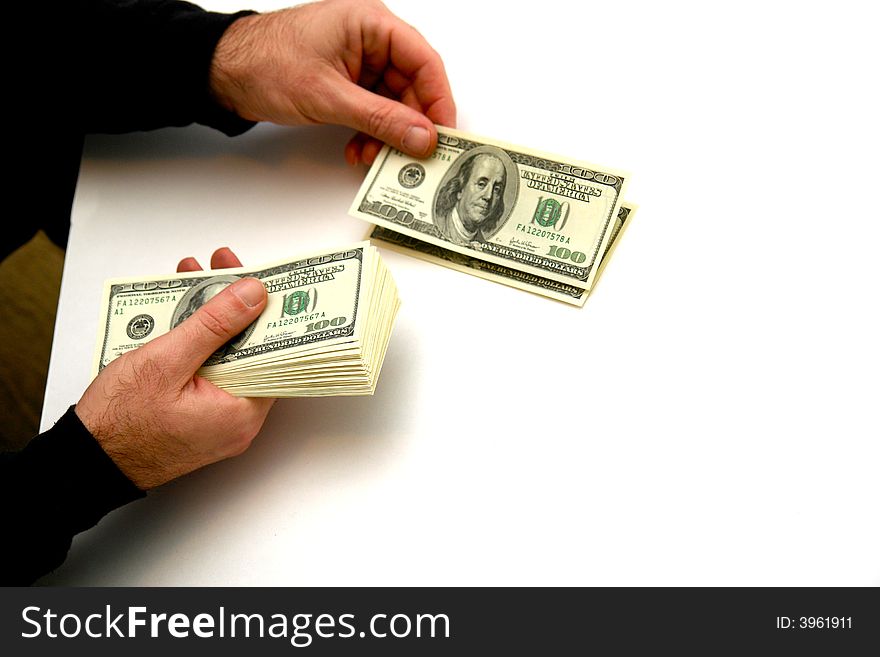 Man counting out hunderd dollar bills in three stacks on white table. Man counting out hunderd dollar bills in three stacks on white table