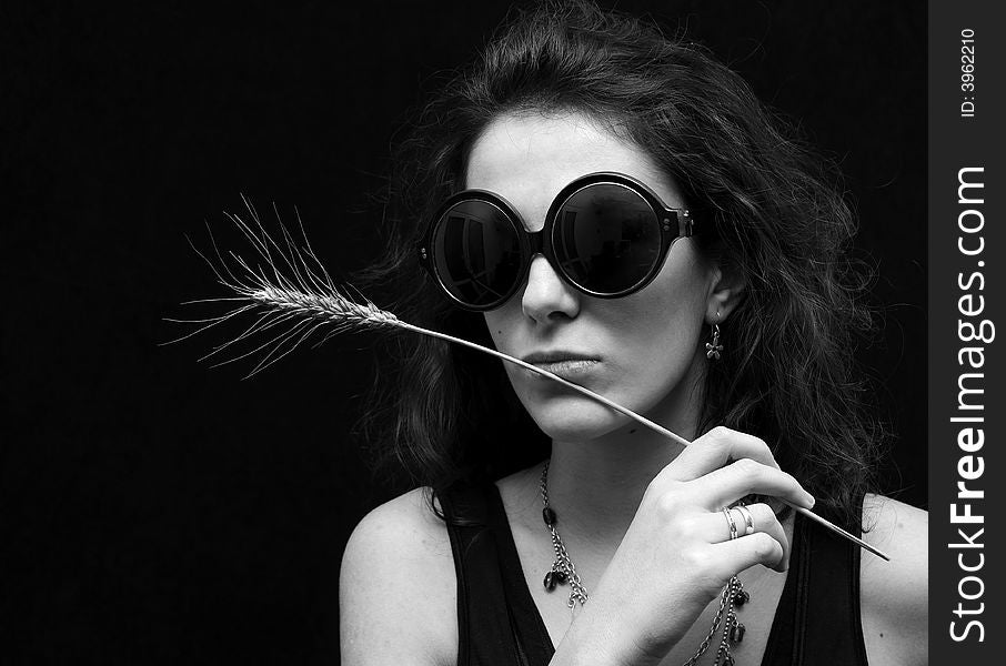 Beautiful brunette on black background with glasses and wheat. Beautiful brunette on black background with glasses and wheat