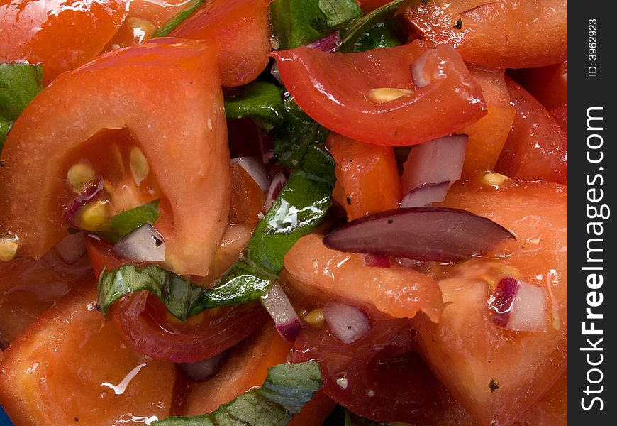 Closeup of a plate full of tomato salad with basil leaves