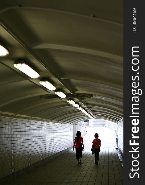 People walking through a dim tunnel in a busy city.