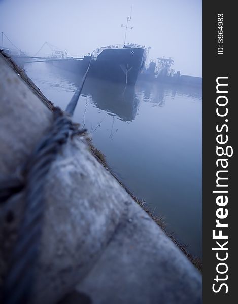 Ship tied with steel wire cable for the stone in the harbor fog. Ship tied with steel wire cable for the stone in the harbor fog