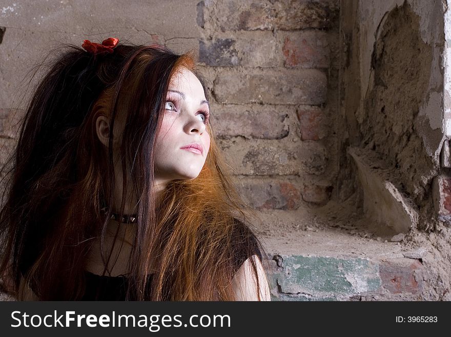 The attractive girl in Gothic style on a background of a brick wall
