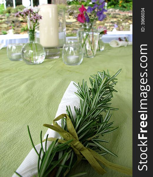 A white napkin place setting tied with freash greenery. A white napkin place setting tied with freash greenery.