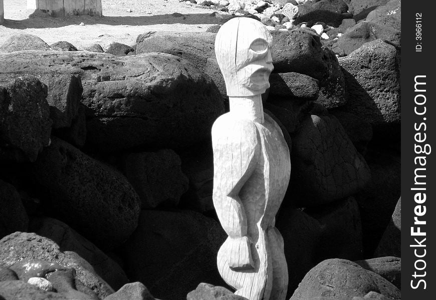 Black and white picture of a Hawaiian Tiki idol tucked in to a bed of volcanic rock. Black and white picture of a Hawaiian Tiki idol tucked in to a bed of volcanic rock.