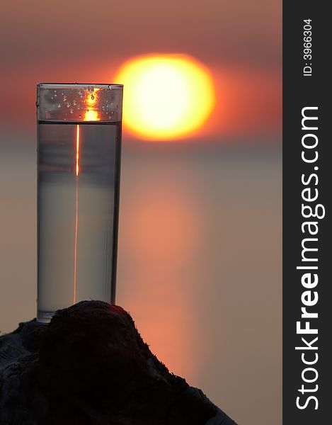 Thin glass with water on sunset background. Thin glass with water on sunset background