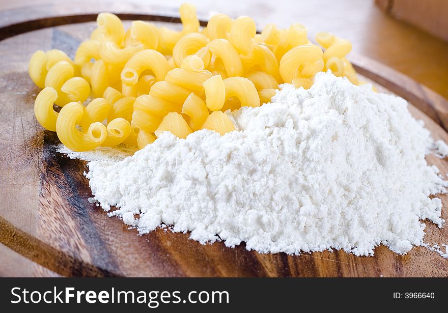 Macaroni and flour on a wooden support. Macaroni and flour on a wooden support