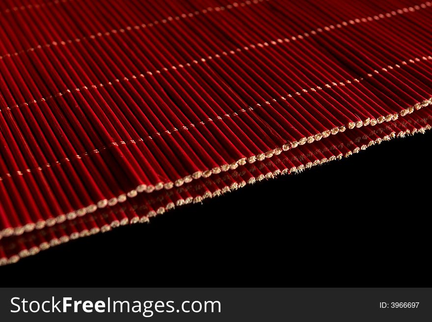 Red bedding  made of thin sticks, on black with reflection