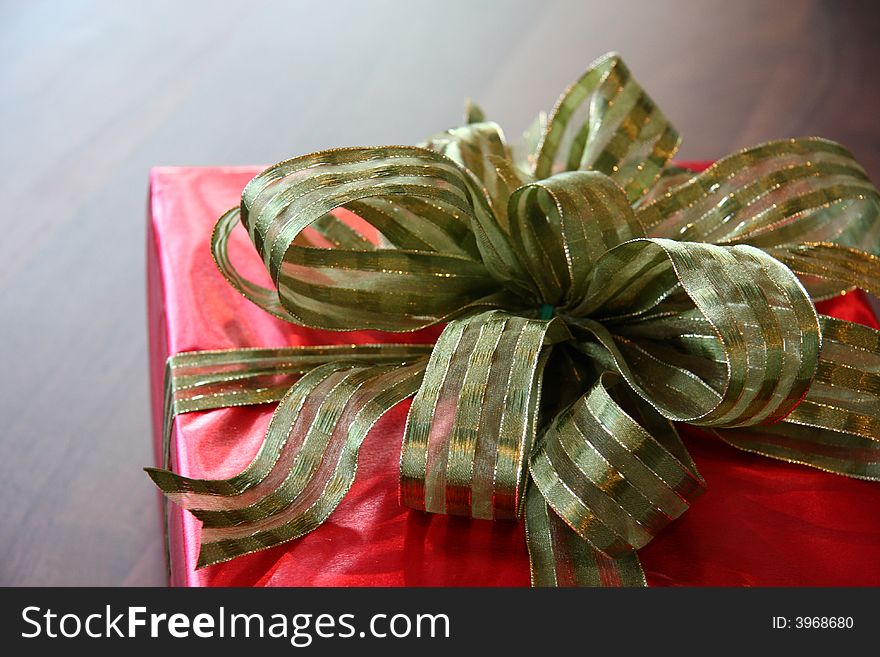 Present set on table with red wrapper and golden bow. Present set on table with red wrapper and golden bow