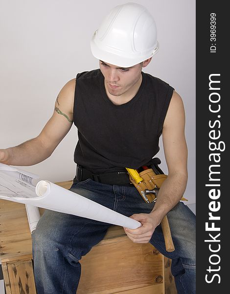 Young man in hard hat looking at blueprints. Young man in hard hat looking at blueprints
