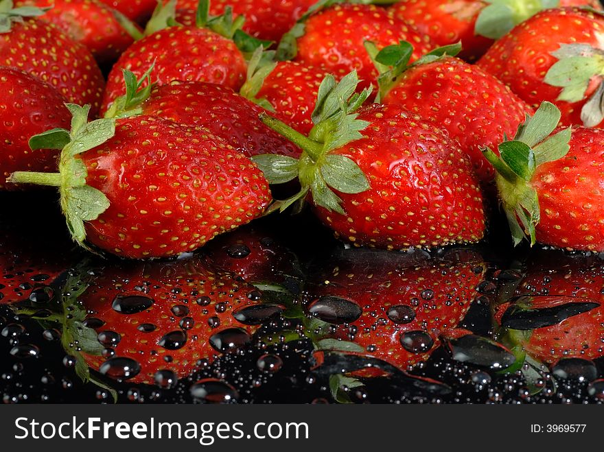 Fresh strawberries with water drops on wet black surface