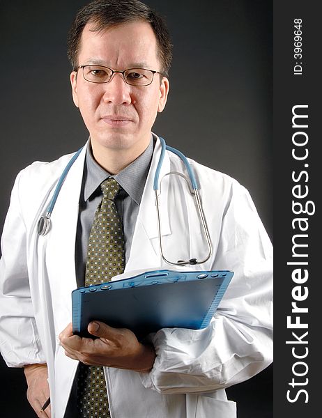 A male doctor holding a clipboard and pen looking into the camera.