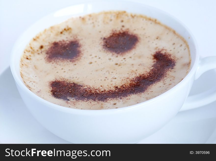 A cup of hot cappuccino with delicate froth and a smiley made of chocolate powder. A cup of hot cappuccino with delicate froth and a smiley made of chocolate powder