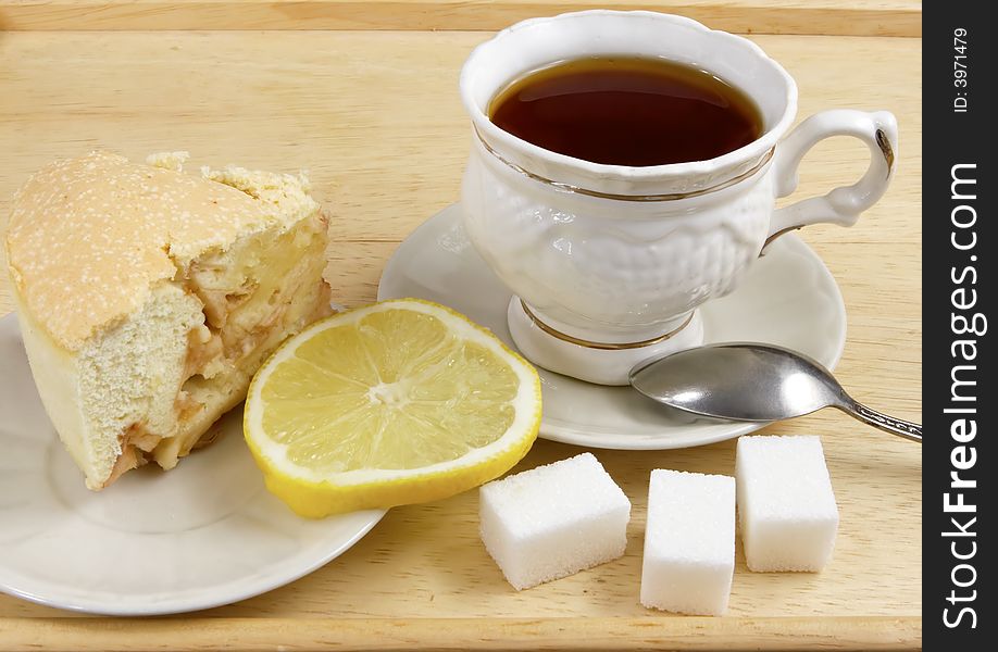 Cup of tea on a tray with a lemon and a biscuit